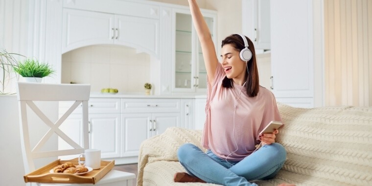 A girl in headphones sits on the couch and is listening to her favorite podcast offline