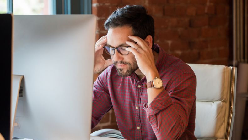 A man keeping his head because he is worried that his monitor is going to sleep too often